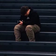 Daniel Bukouricz sitting on the bleachers, checking the back of his camera.